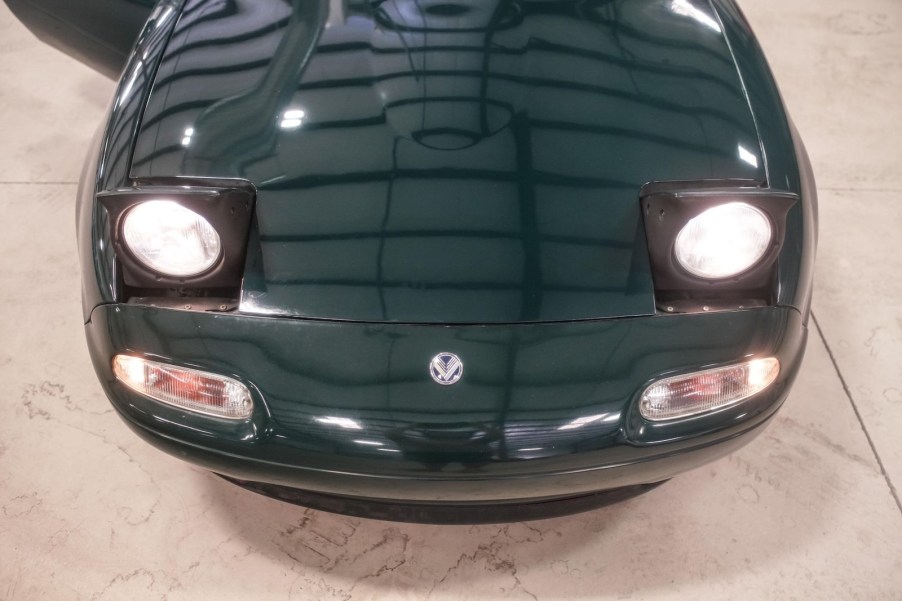 The hood and pop-up headlights of a British Racing Green JDM Eunos Roadster.