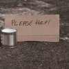 "Please help" cardboard sign and collection cup from a panhandler beggar