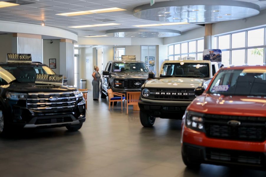 A Ford dealership showroom with a Maverick in the foreground and an F-150 pickup truck in the background.