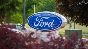 Ford sign at a dealership, a Mustang Mach-E visible in the background.