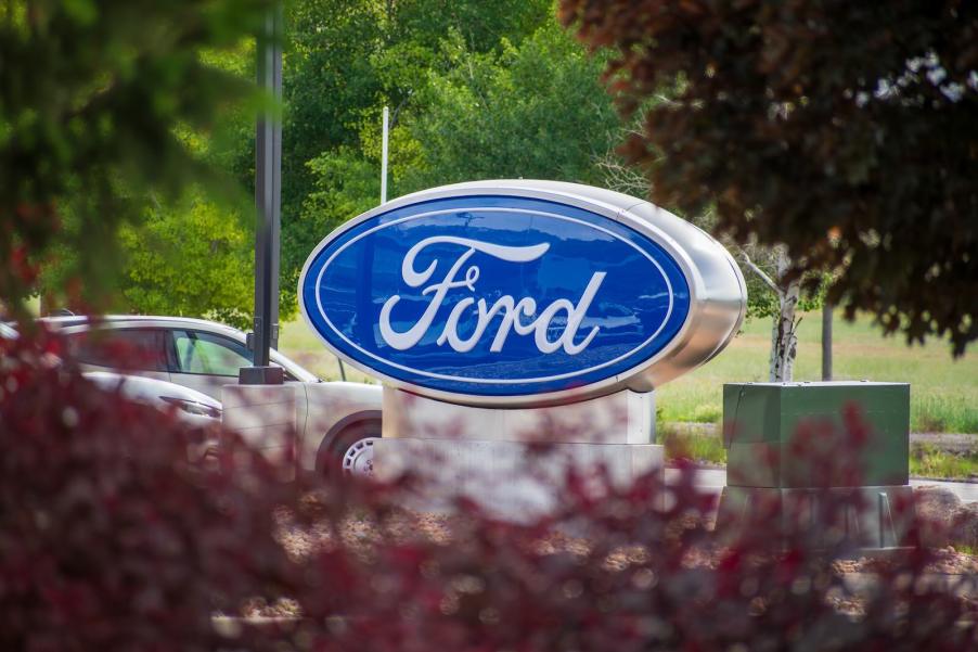 Ford sign at a dealership, a Mustang Mach-E visible in the background.