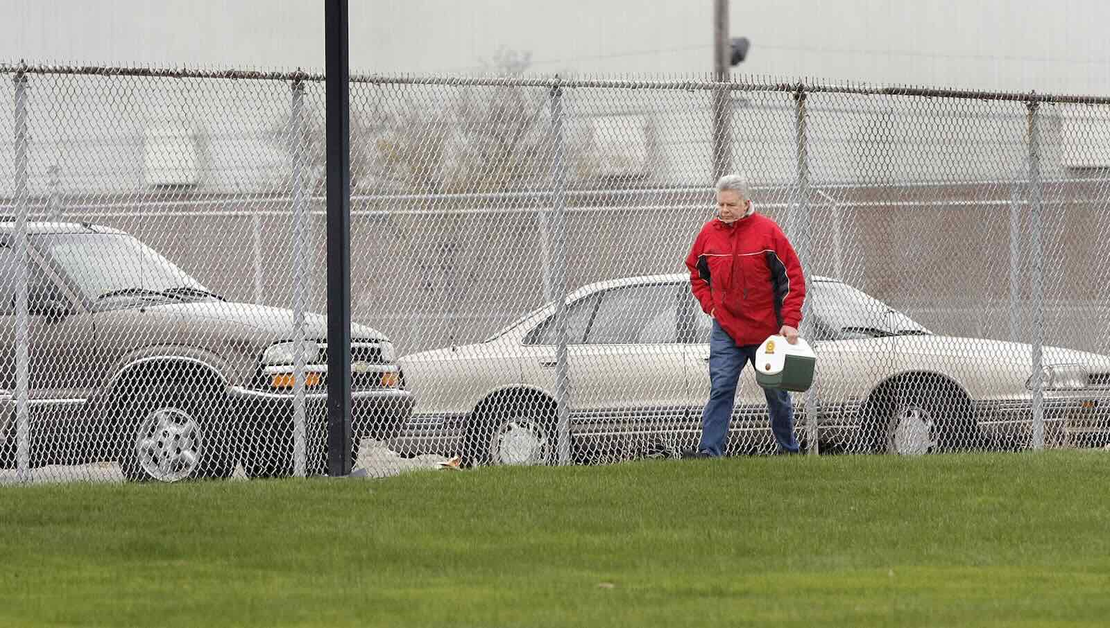 General Motors' factory worker carrying his lunch box across a plant's lawn.