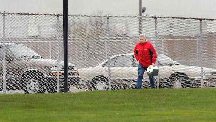 General Motors' factory worker carrying his lunch box across a plant's lawn.