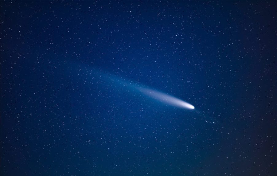 White meteor streaking across a blue sky, stars visible in the background.
