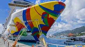 Cruise ship with a colorful paint job tied to a dock.