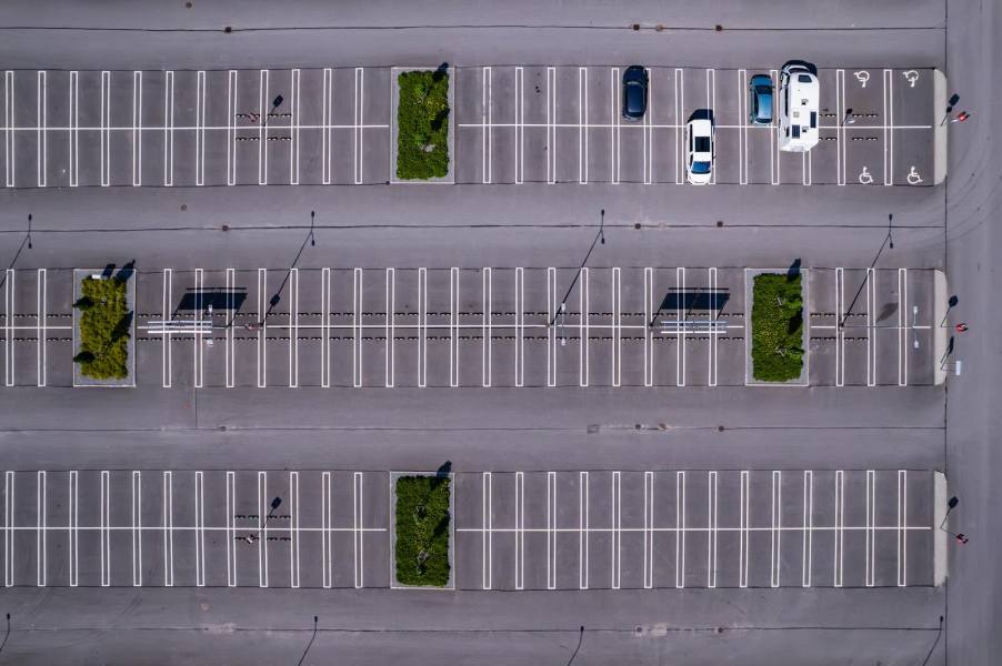 Overhead view of a parking lot with cars, RVs, and empty spaces