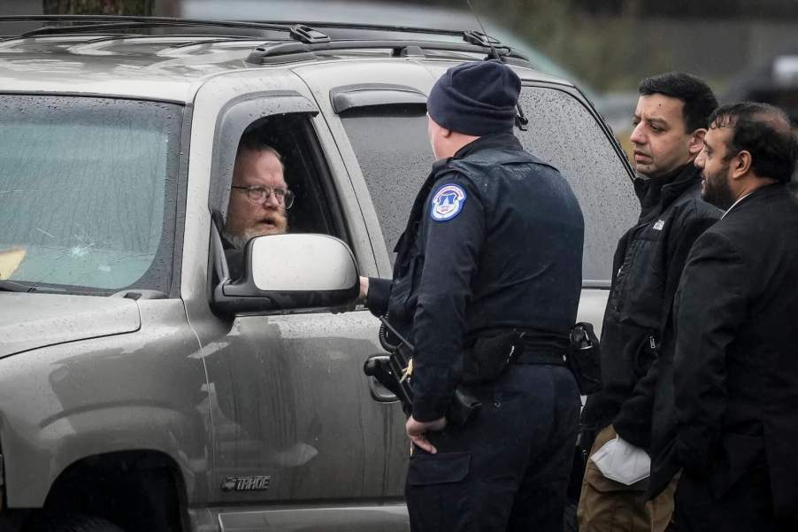 Three police offices talking to a Chevrolet Suburban driver during a traffic stop.