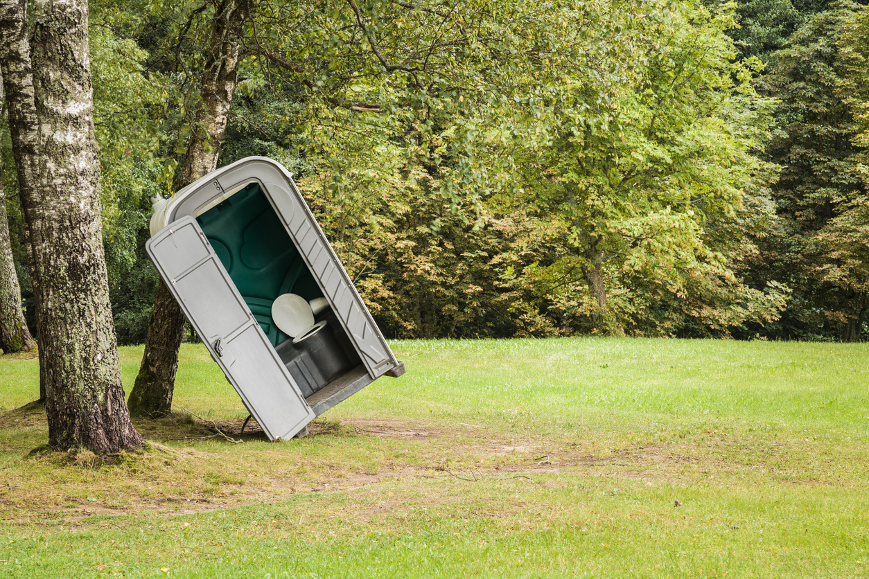 A porta potty leaning to the side