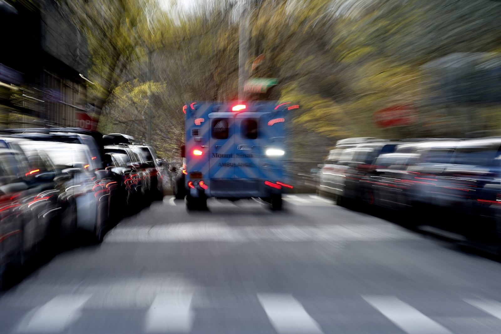 Ambulance racing down a residential street and away into the distance.