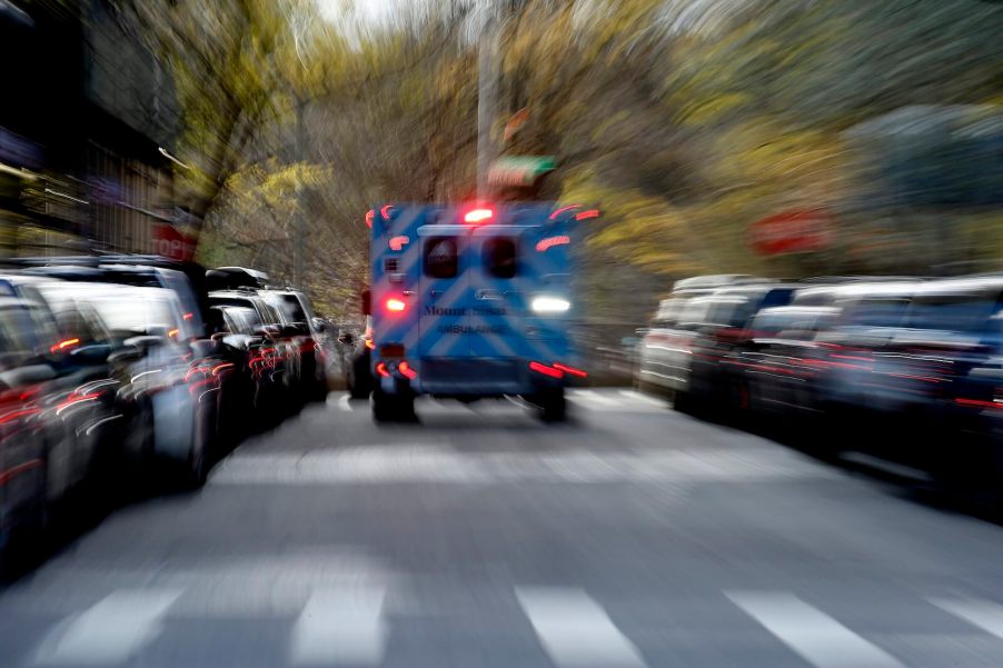 Ambulance racing down a residential street and away into the distance.