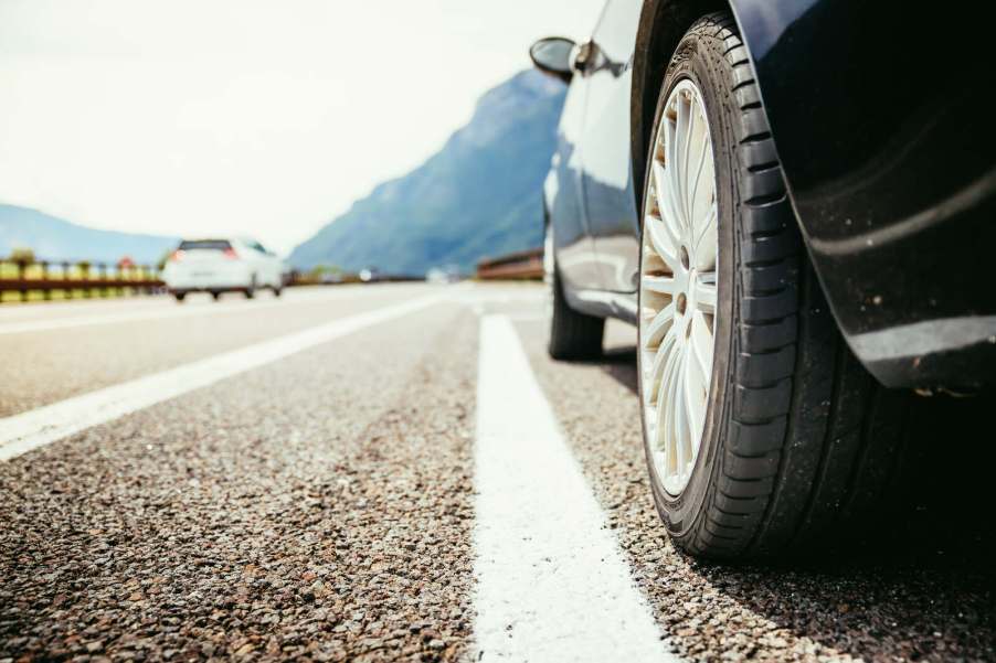 A car merges onto a highway in very close low left rear view
