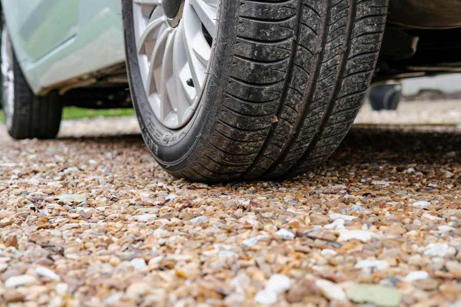 A car parked on gravel in very close low left rear angle view