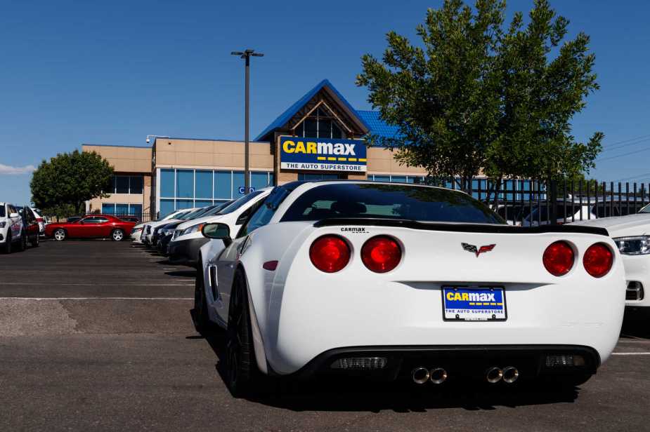 A CarMax lot with a white Chevy Corvette parked in rear view