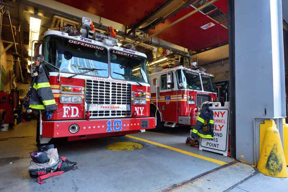 FDNY trucks parked inside fire station view from open doors