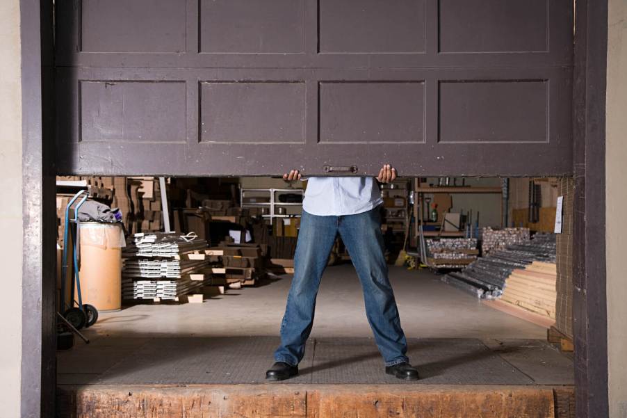 A man lifts a residential garage door from the inside