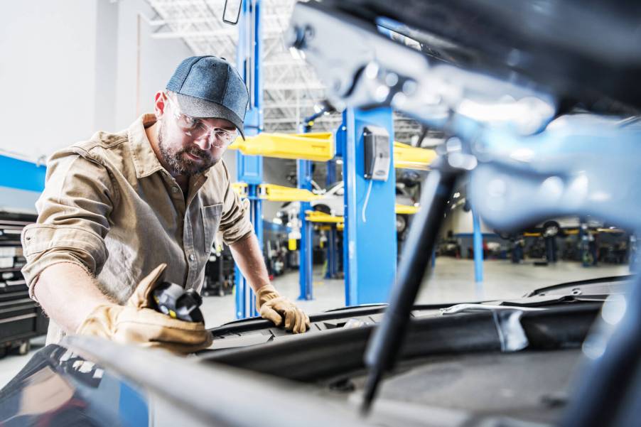 A mechanic working under a car hood