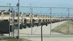 Oshkosh Defense JLTV models lined up inside a chain link fence