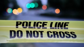 "Police line, do not cross" tape strung across the frame in front of a road