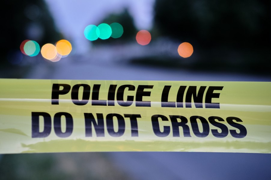 "Police line, do not cross" tape strung across the frame in front of a road