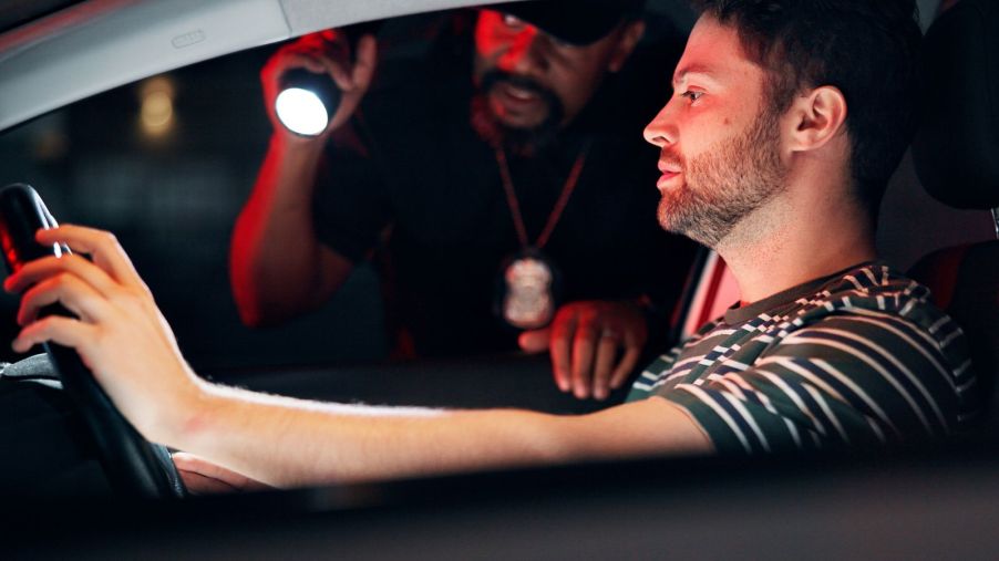 A police officer talks to driver while holding flashlight