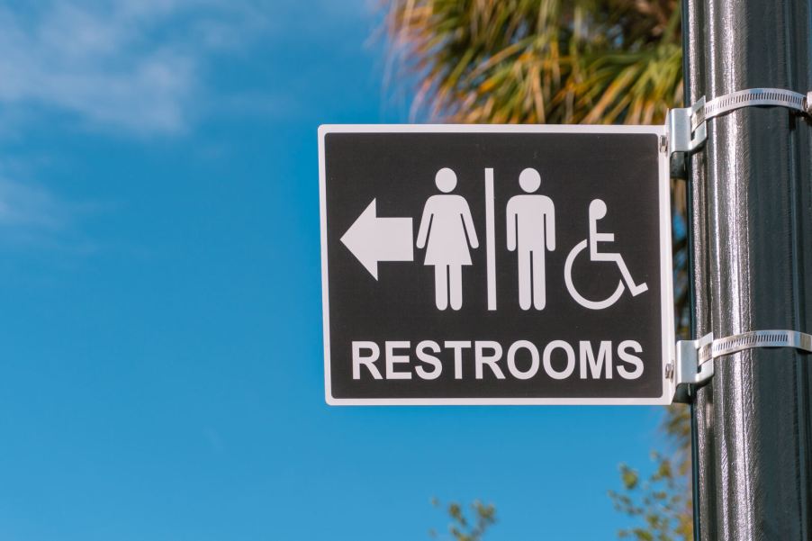 A restroom street sign with a palm tree in the background
