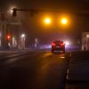 A small town Main St. traffic light intersection at night with a dark car stopped