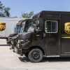 A row of brown UPS trucks parked in left profile angle view