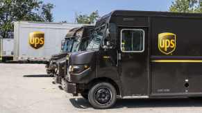 A row of brown UPS trucks parked in left profile angle view