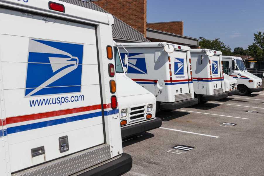 USPS mail trucks parked outside a distribution center