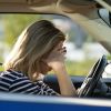 A blonde female driver covers her face