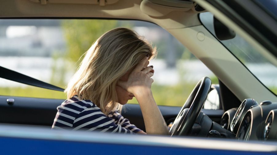 A blonde female driver covers her face