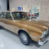 A gold 1979 Plymouth Volare Custom Sedan in a showroom in right front angle view