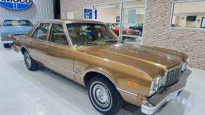 A gold 1979 Plymouth Volare Custom Sedan in a showroom in right front angle view