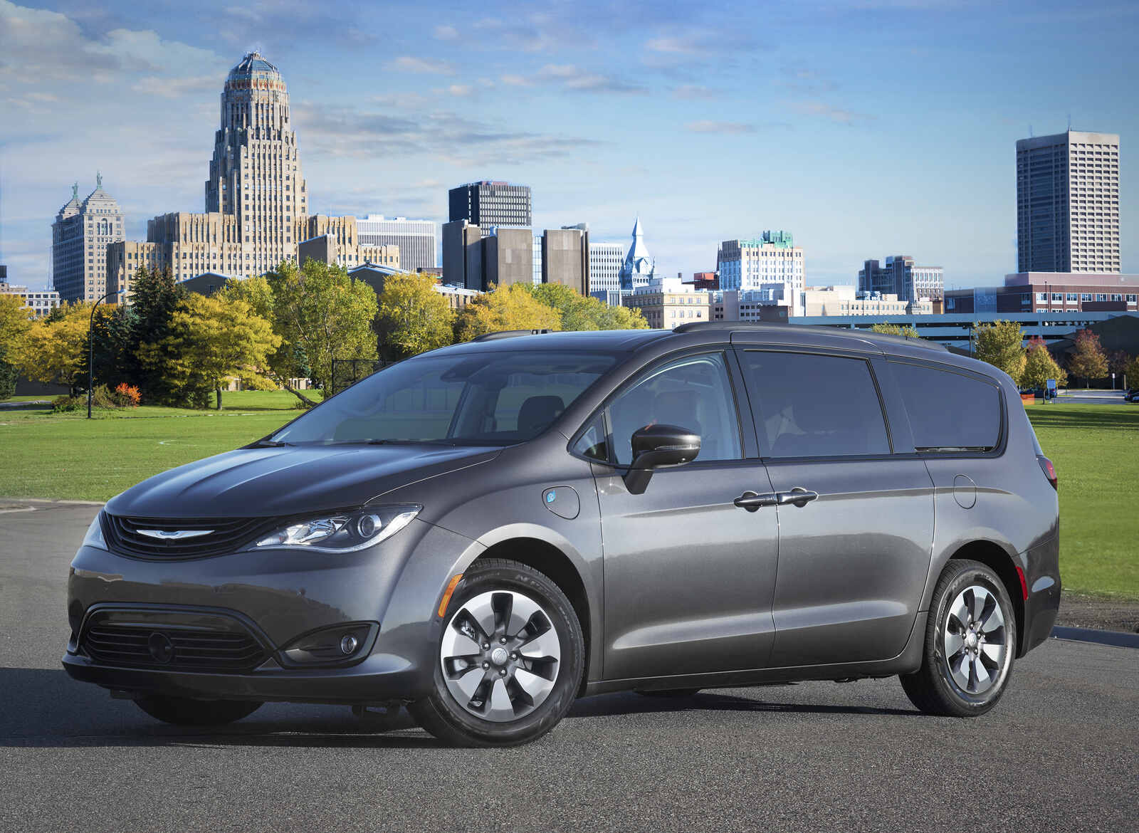 A grey 2018 Chrysler Pacifica Hybrid parked in left front angle view in front of a city skyline