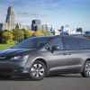 A grey 2018 Chrysler Pacifica Hybrid parked in left front angle view in front of a city skyline
