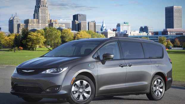 A grey 2018 Chrysler Pacifica Hybrid parked in left front angle view in front of a city skyline