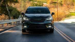 A black 2022 Chrysler Pacifica driving on a highway in direct front view