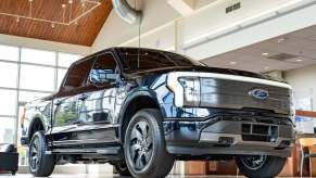 A black 2022 Ford F-150 Lightning Lariat parked inside a dealer showroom in low right front angle view