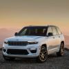 A white 2024 Jeep Grand Cherokee 4xe parked in left front angle view at dusk