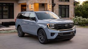 A blue 2025 Ford Expedition parked in front of a luxury home