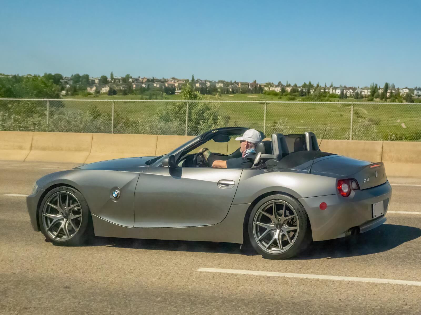 Man drives his BMW Z4 roadster convertible along the highway.