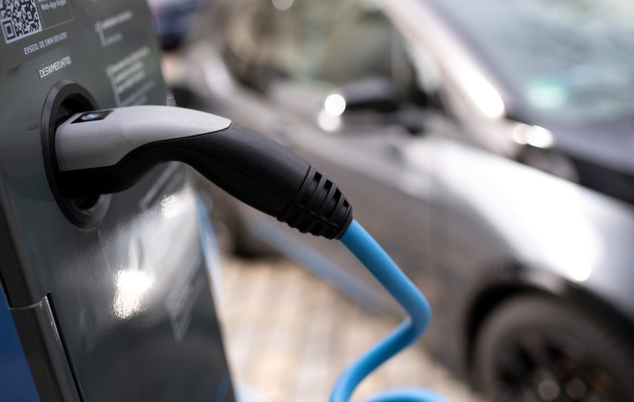 BMW i3 behind a BMW-branded EV charger cable.