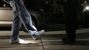 Basketball coach walks along line on the pavement, toward a police officer. during a field sobriety test.