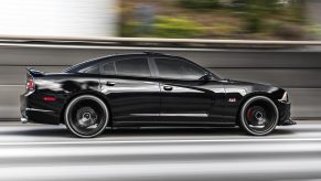 Black Dodge Charger sedan racing down the highway.