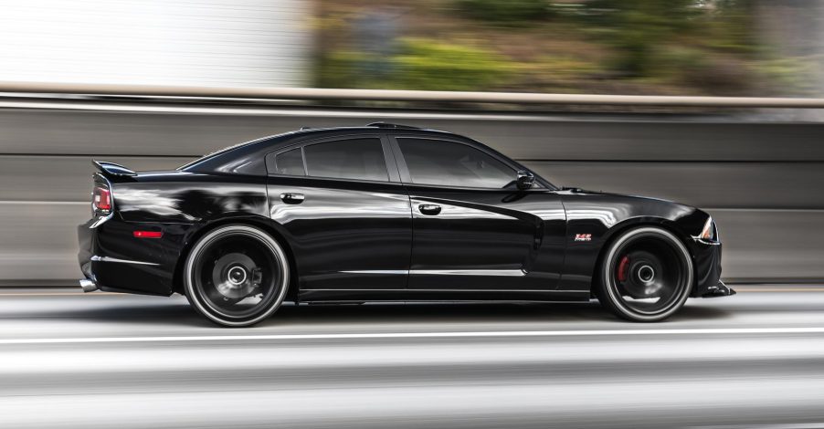 Black Dodge Charger sedan racing down the highway.