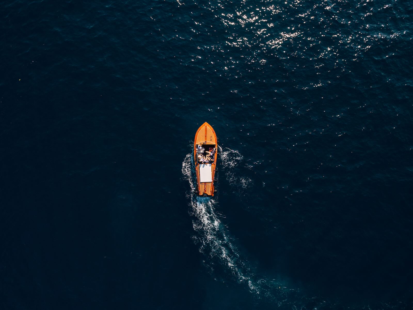 Overhead view of a small wooden boat on the open ocean.