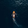 Overhead view of a small wooden boat on the open ocean.