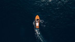 Overhead view of a small wooden boat on the open ocean.