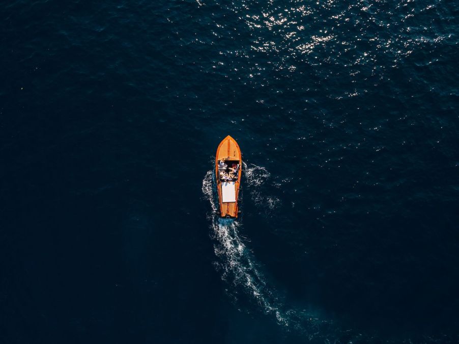 Overhead view of a small wooden boat on the open ocean.
