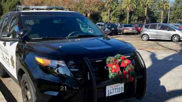 Police cruiser with a California Exempt license plate and a wreath on its grill guard.